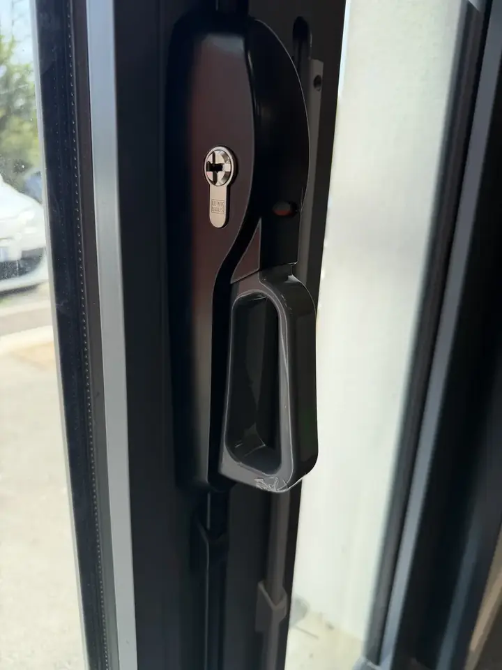 Poignée et serrure neuves avec cylindre Winkhaus sur une porte en aluminium
