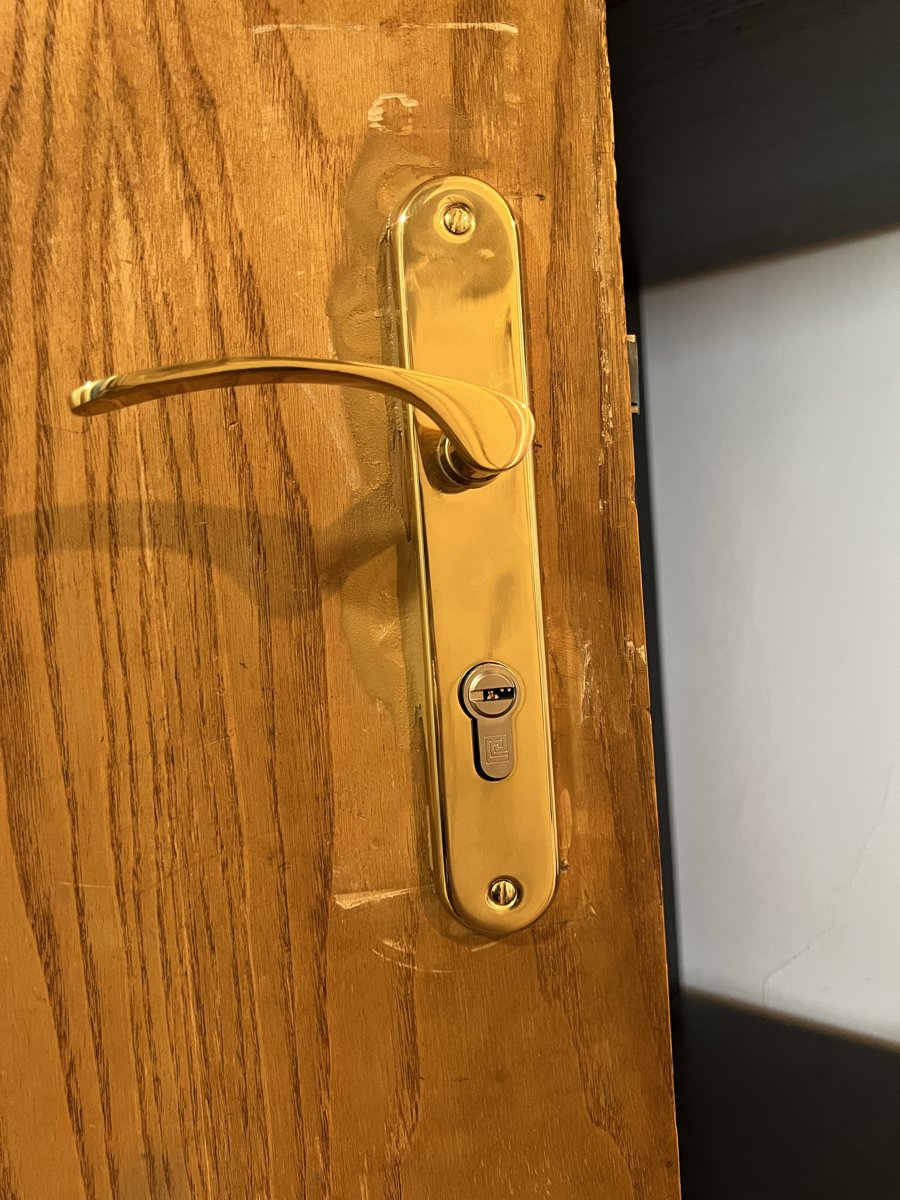 Poignée et plaque en laiton avec cylindre de sécurité sur une porte en bois