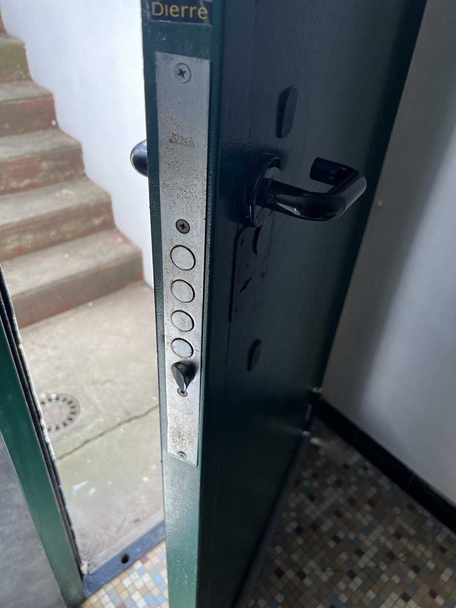 Serrure multipoints et poignée noire sur une porte d'entrée métallique